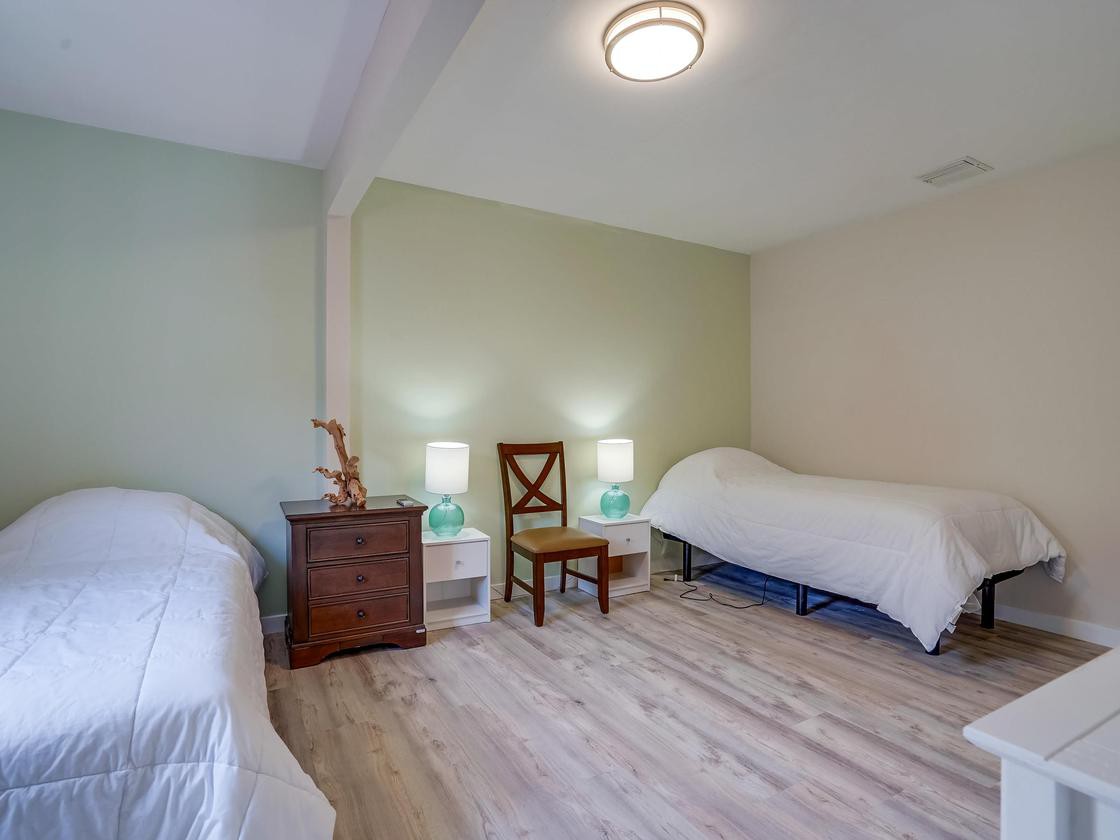 A cozy bedroom with two single beds, soft lighting, and wooden floors.