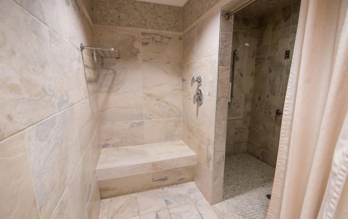 A modern bathroom shower area with tiled walls and a built-in bench.