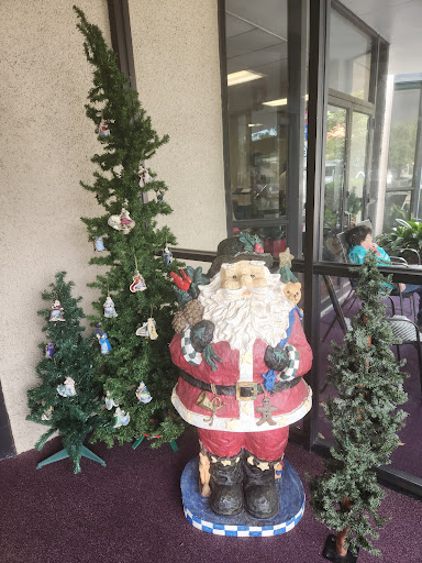 A festive display featuring a statue of Santa Claus surrounded by decorated Christmas trees.