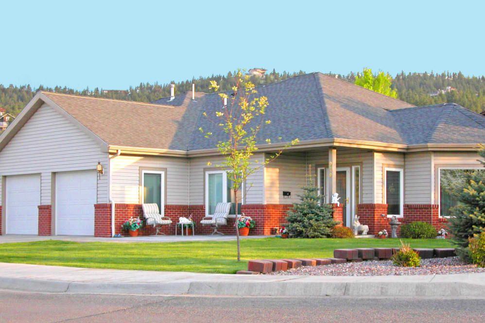 A suburban house with a well-maintained front yard and clear sky background.