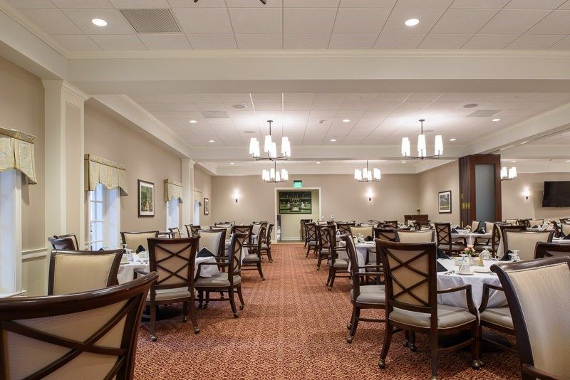 An elegant and spacious dining room with neatly arranged tables and chairs, featuring soft lighting and tasteful decor.