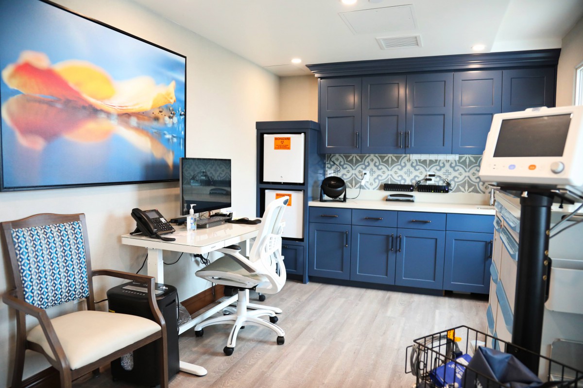 A modern home office featuring a sleek desk, computer setup, and stylish blue cabinetry.