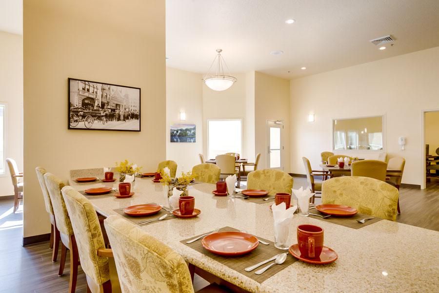 A beautifully set dining room table with red plates and mugs, ready for a meal.