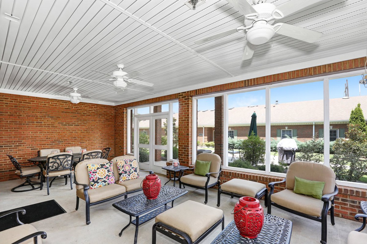 A bright sunroom with comfortable seating and large windows overlooking a patio.