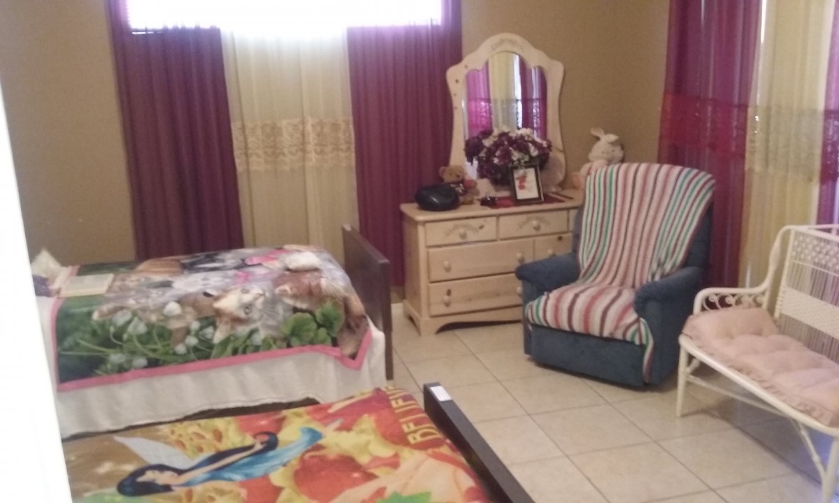 A cozy bedroom with a bed, dresser, and a comfortable chair.