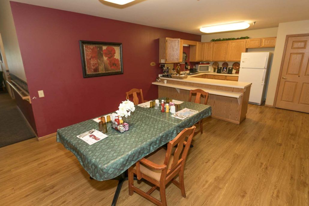 A dining area with a table set for a meal, adjacent to a kitchen.