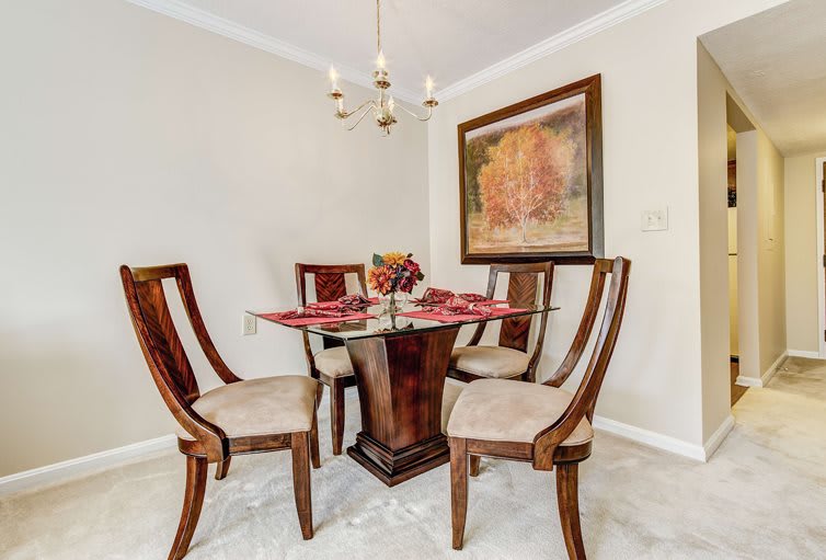 A cozy dining room with a wooden table and four chairs, enhanced by elegant artwork and a chandelier.
