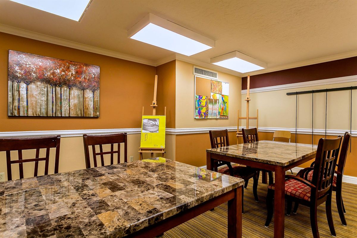 A cozy dining room with marble-topped tables and chairs, decorated with artwork and warm lighting.