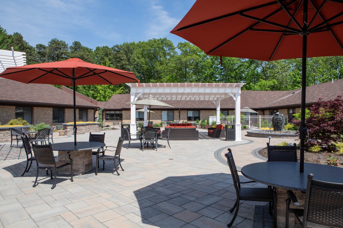 A sunny outdoor patio area with tables, chairs, and umbrellas.
