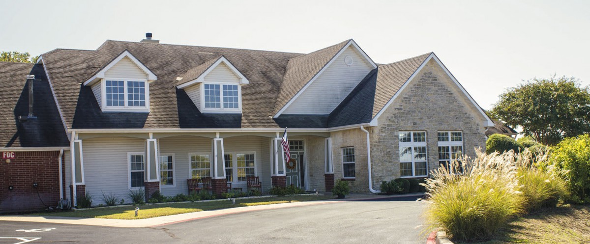 A residential house with a driveway and front porch on a sunny day.