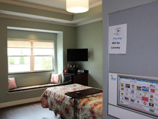 A cozy room featuring a bed, a television, and natural light from the window.