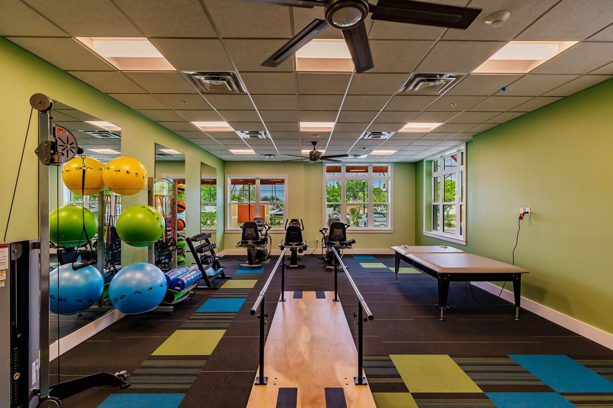 A bright and well-equipped fitness and therapy room with exercise equipment and colorful decor.
