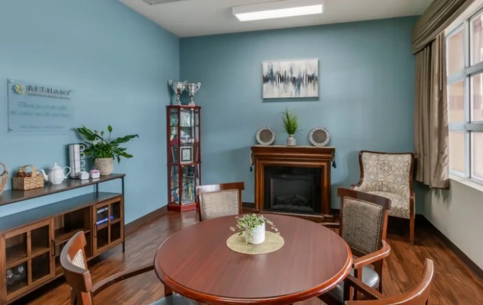 A cozy living room with a round table, chairs, fireplace, and decor elements on blue walls.