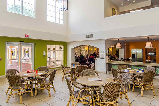 A spacious and well-lit dining area with several tables and chairs, featuring modern decor in a cafe setting.