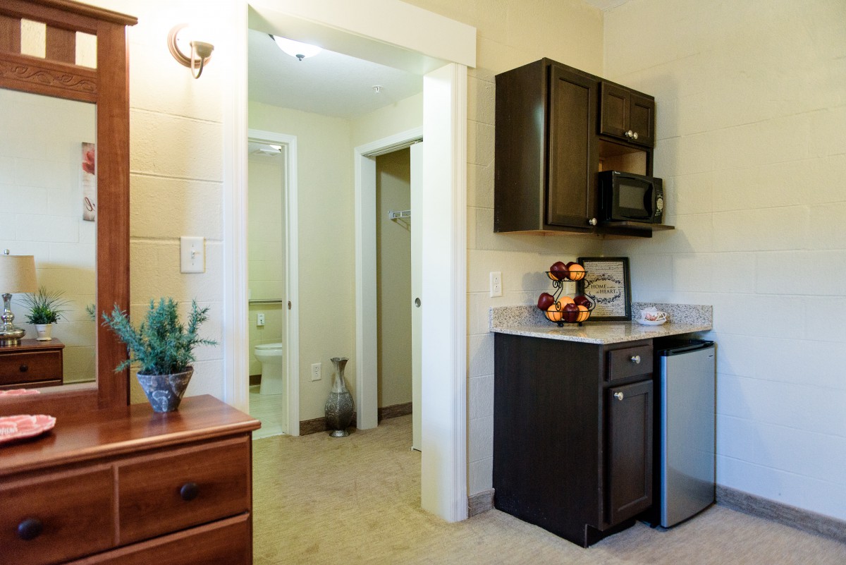A cozy kitchenette in a small apartment featuring a microwave, refrigerator, and simple decor.