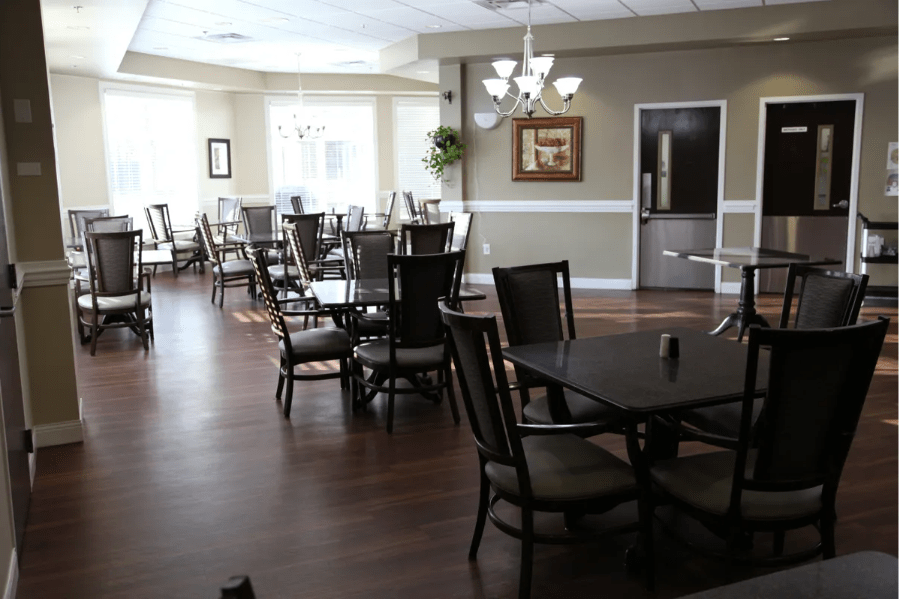 A spacious dining area with neatly arranged tables and chairs, well-lit by ceiling lights.