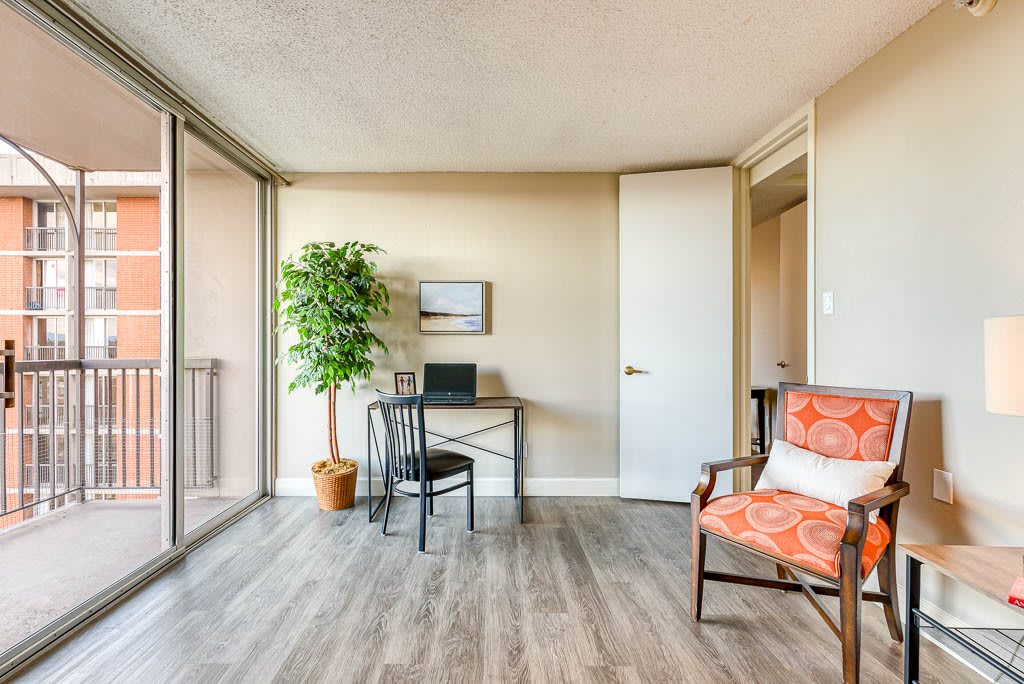 A small, modern office space with a desk, chair, and potted plant next to a large window.