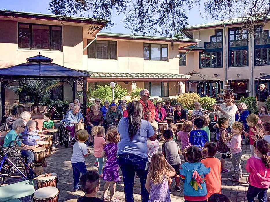 A diverse group of people, including children and adults, enjoy an outdoor community gathering.