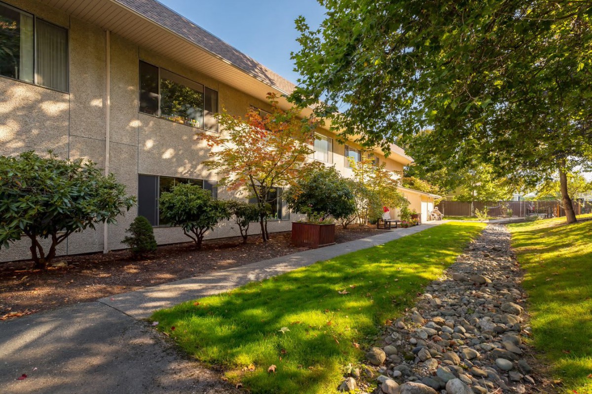 A well-maintained apartment building with a landscaped garden and a sunny pathway.