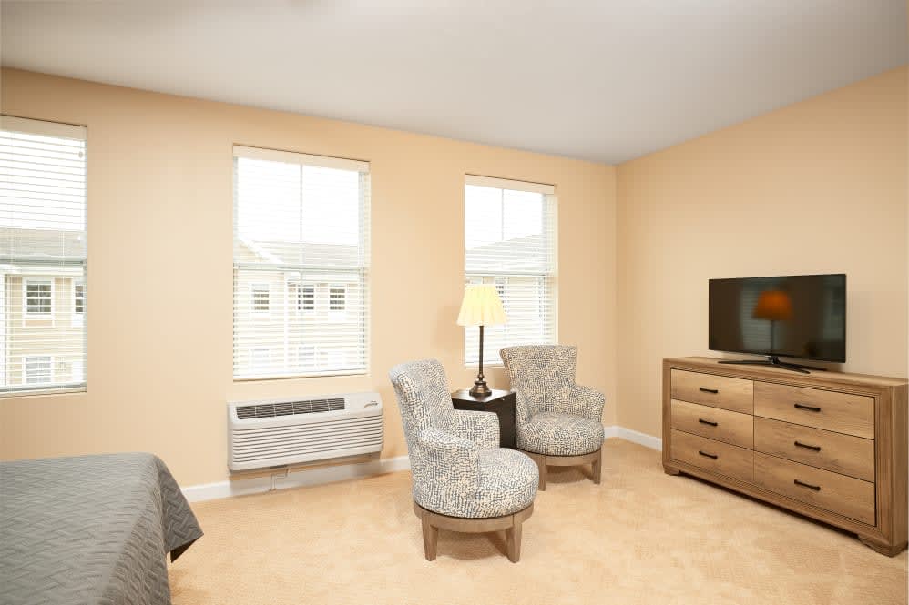 A cozy living room with two patterned chairs, a small table, and a television.