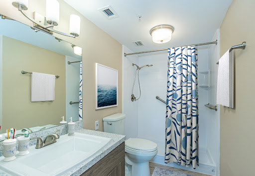 A modern bathroom featuring a clean aesthetic with a blue and white shower curtain, elegant lighting, and stylish decor.