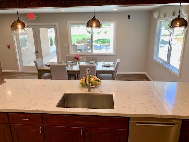 Modern kitchen with a view of the dining area, featuring a sleek countertop and pendant lighting.