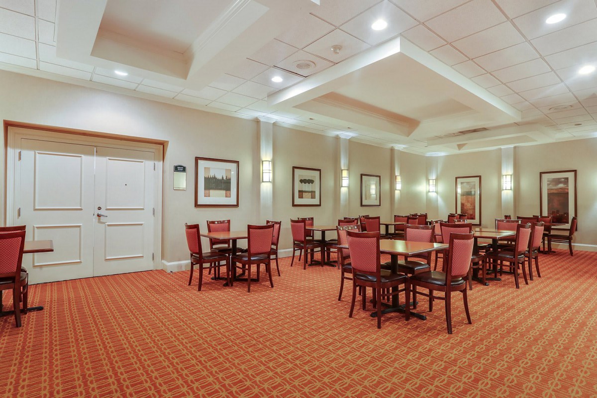 A well-lit conference room with red chairs and tables arranged for meetings.