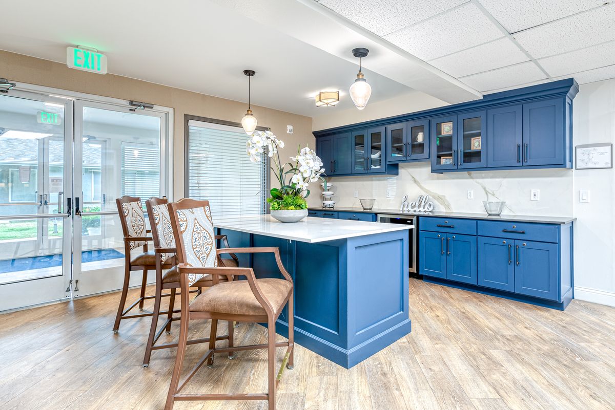 A modern kitchen with vibrant blue cabinets and a central island, featuring bar stools and pendant lighting.