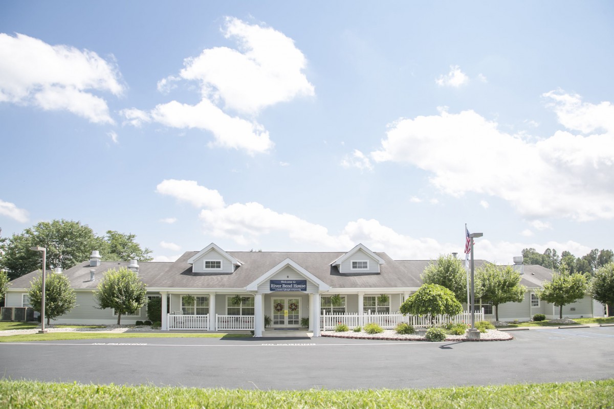 A sunny day with a building surrounded by trees and a parking lot.