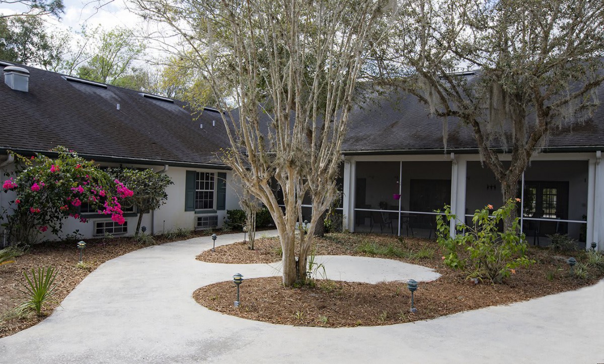 A peaceful residential home with a landscaped driveway and a central tree.