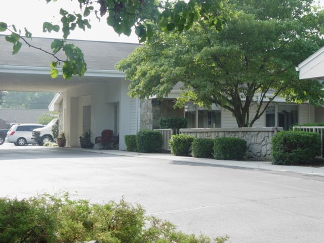A building entrance surrounded by trees and a driveway.