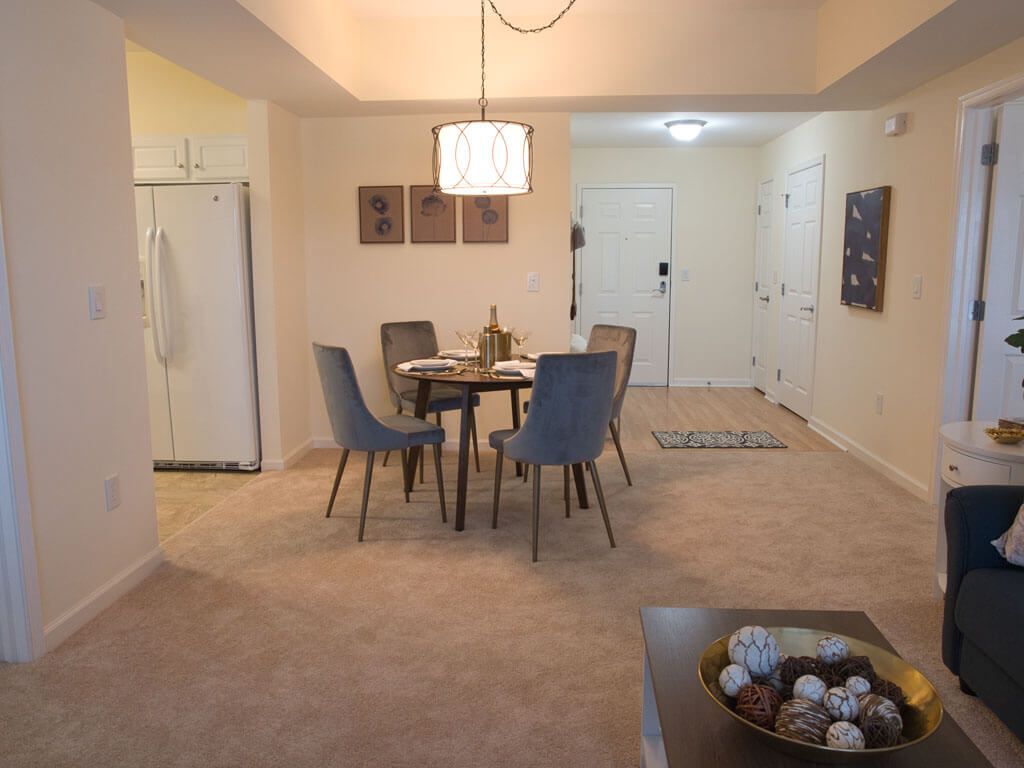 A cozy dining area featuring a round table with five chairs, accented by warm lighting and tasteful decor.
