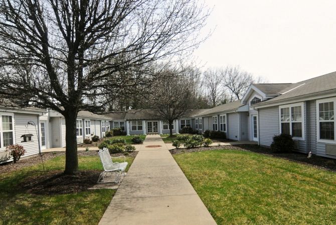 A quiet suburban residential area with a central pathway flanked by houses and trees.