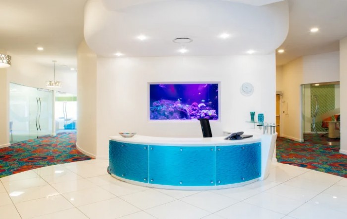 A modern reception area with a blue curved desk and an aquarium display on the wall.