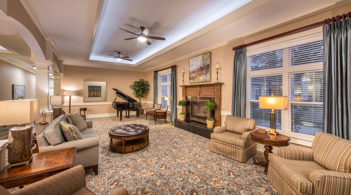 A cozy living room with a piano, fireplace, and comfortable seating arrangement.