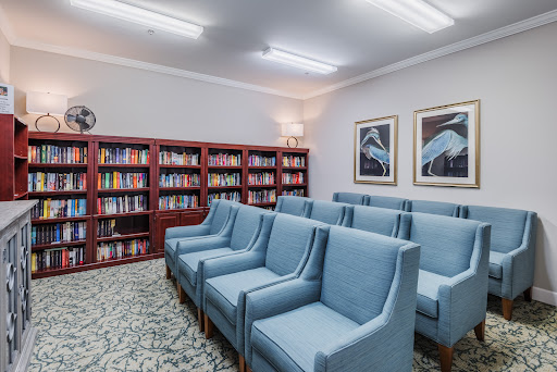 A cozy library space featuring blue chairs arranged for reading, complemented by shelves filled with books.