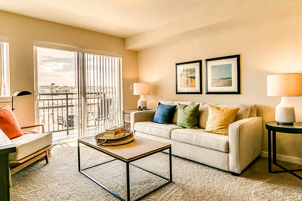 A cozy living room with a modern sofa, decorative pillows, and a stylish coffee table overlooking a balcony.