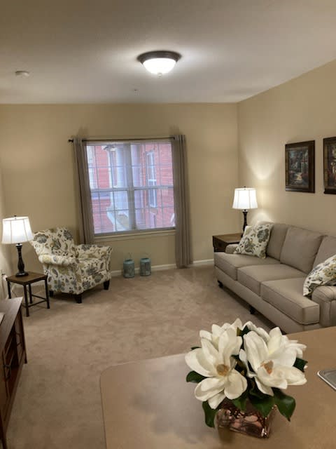 A cozy living room with a sofa, armchair, and warm lighting.