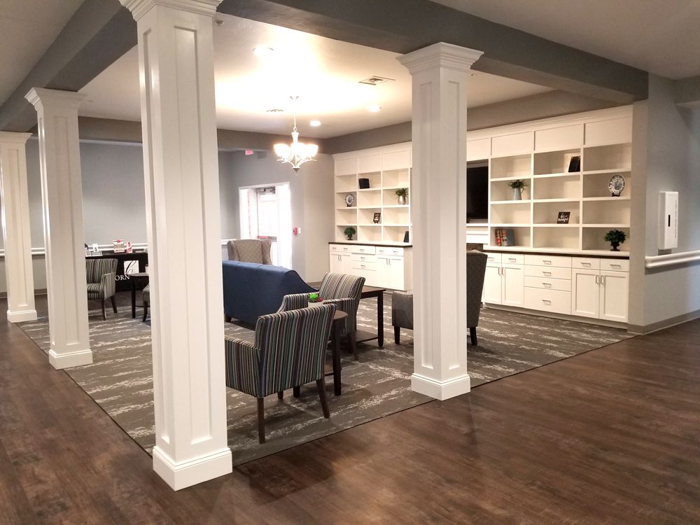 A spacious living area featuring comfortable seating, built-in shelves, and elegant pillars.