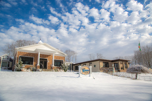 A peaceful winter scene featuring a brick building surrounded by snow and a beautiful cloudy sky.