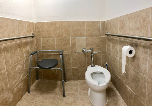 An accessible bathroom featuring a toilet and safety grab bars.