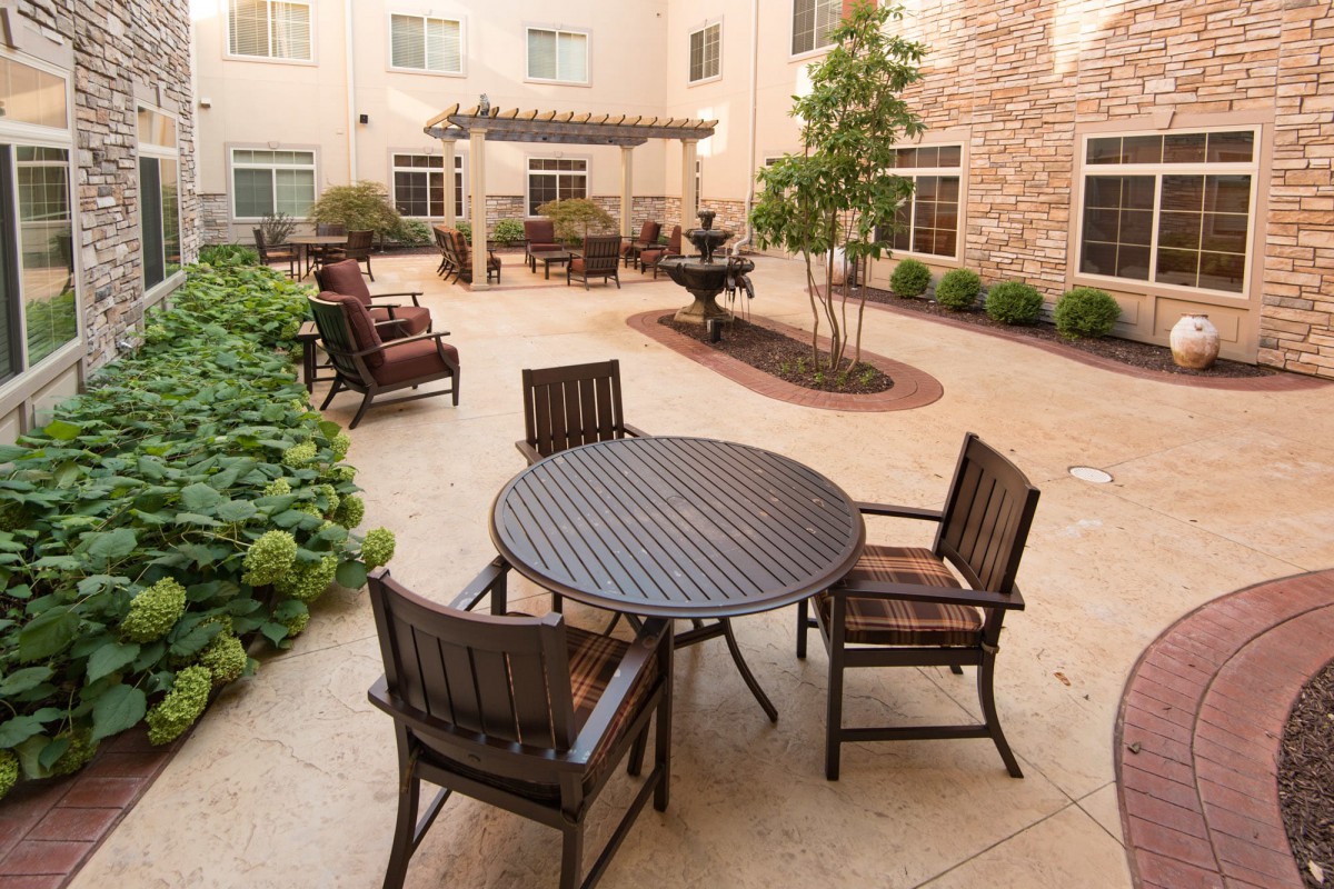 A serene courtyard with a table and chairs surrounded by lush greenery.