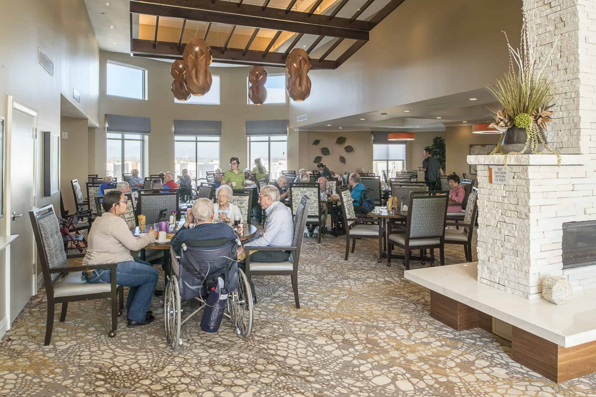 A busy dining area with numerous people enjoying a meal, featuring large windows and a welcoming atmosphere.
