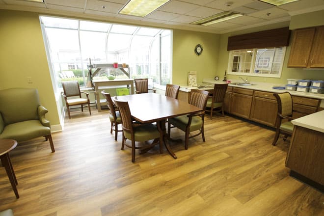 A spacious conference room with a large meeting table, chairs, and ample natural light from the windows.