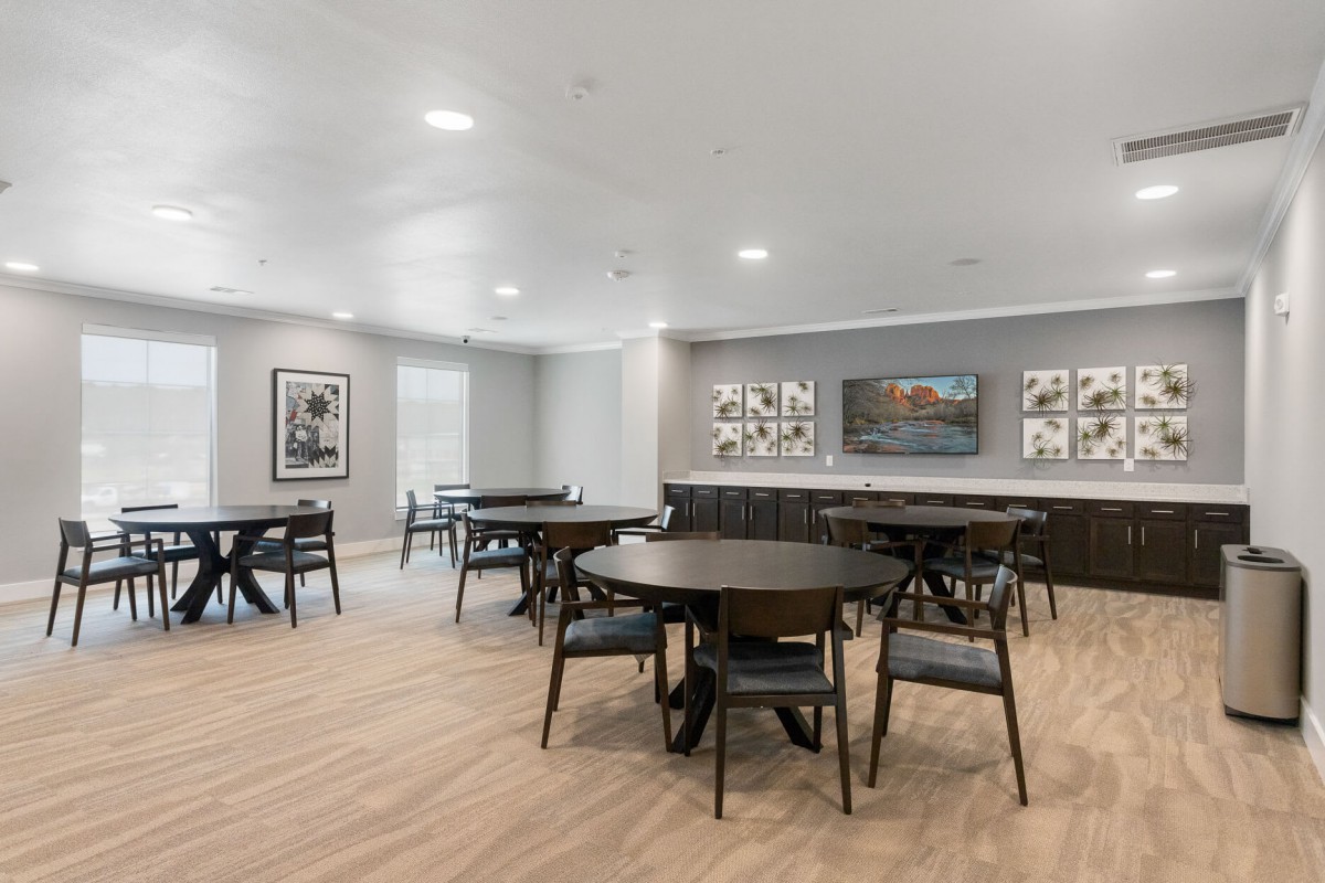 A modern meeting room with round tables, chairs, and decorative wall art.