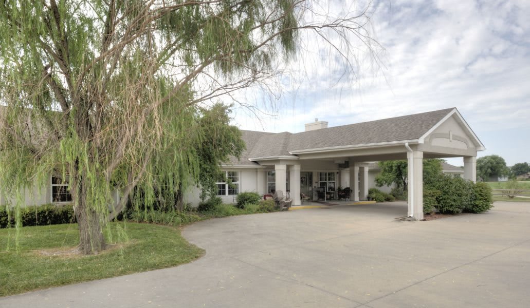 A suburban house with a large driveway and surrounding greenery.