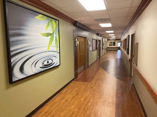 A serene and modern hallway featuring decorative artwork and wooden flooring.