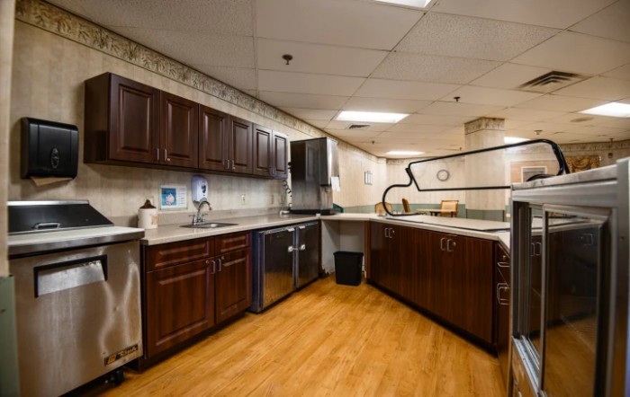 A modern kitchen interior with dark cabinets and wooden flooring.