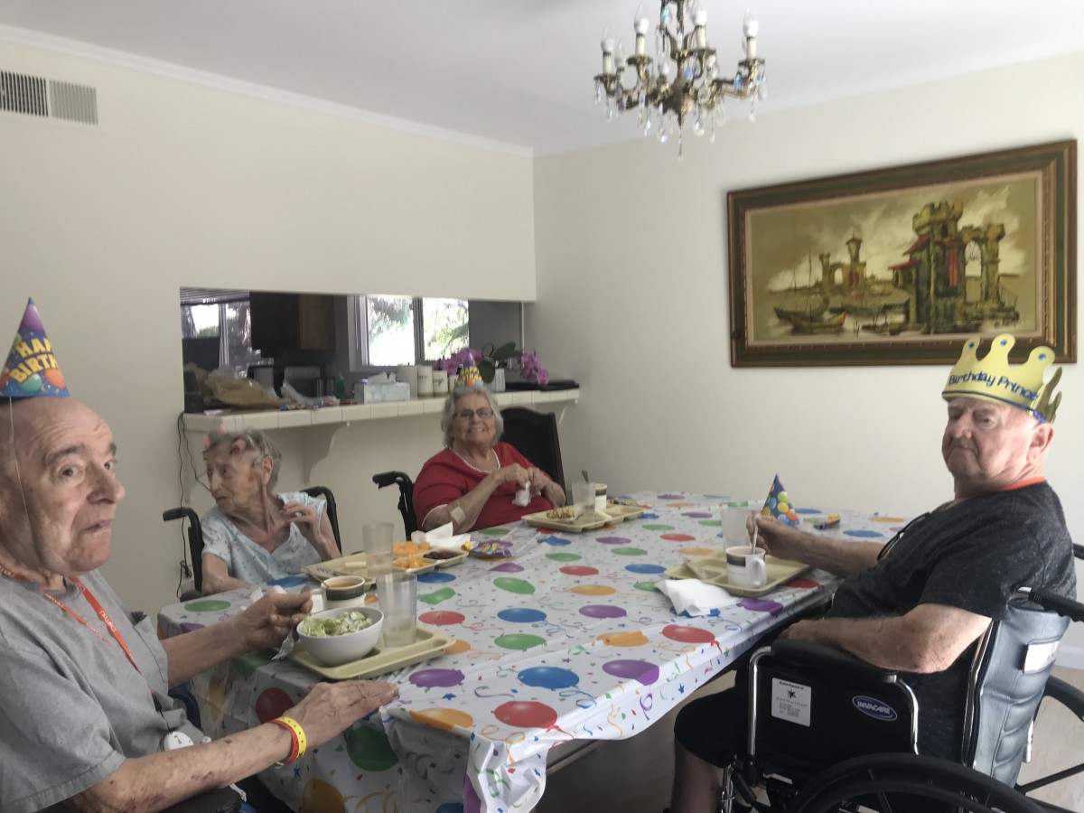 A group of elderly individuals sitting around a dining table, enjoying a meal together.