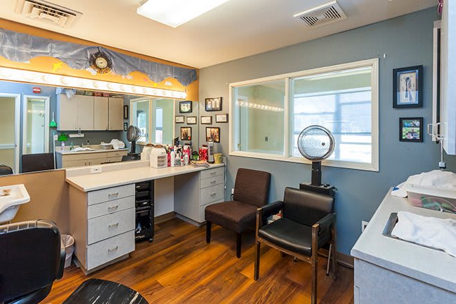 A cozy salon vanity area with a mirror, beauty products, and comfortable seating.